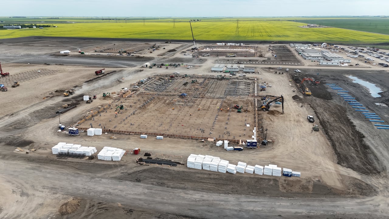 Photos taken from a drone show workers and heavy machinery at a construction site.