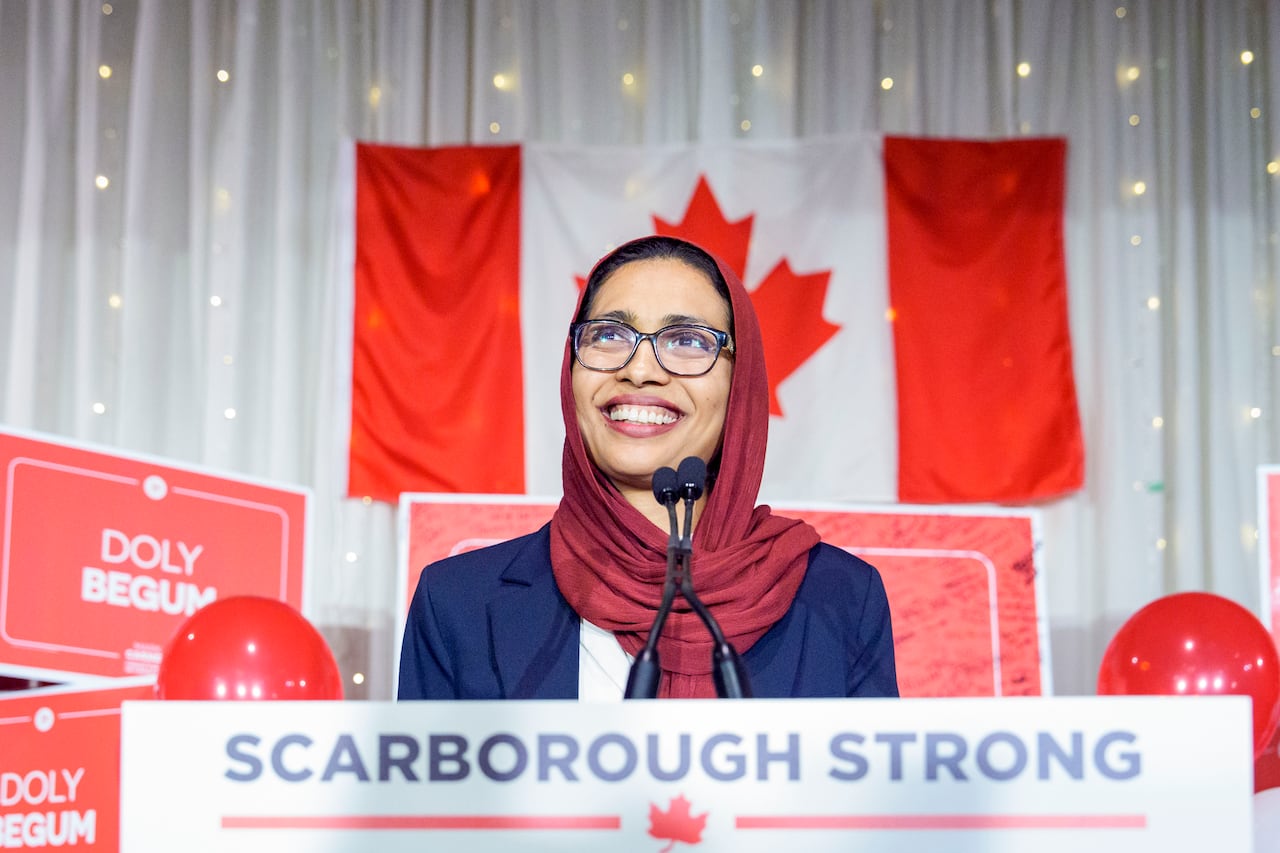 A woman stands in front of a podium, smiling. 