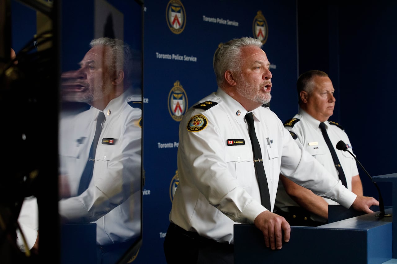 Man in police uniform standing behind podium speaking into microphone