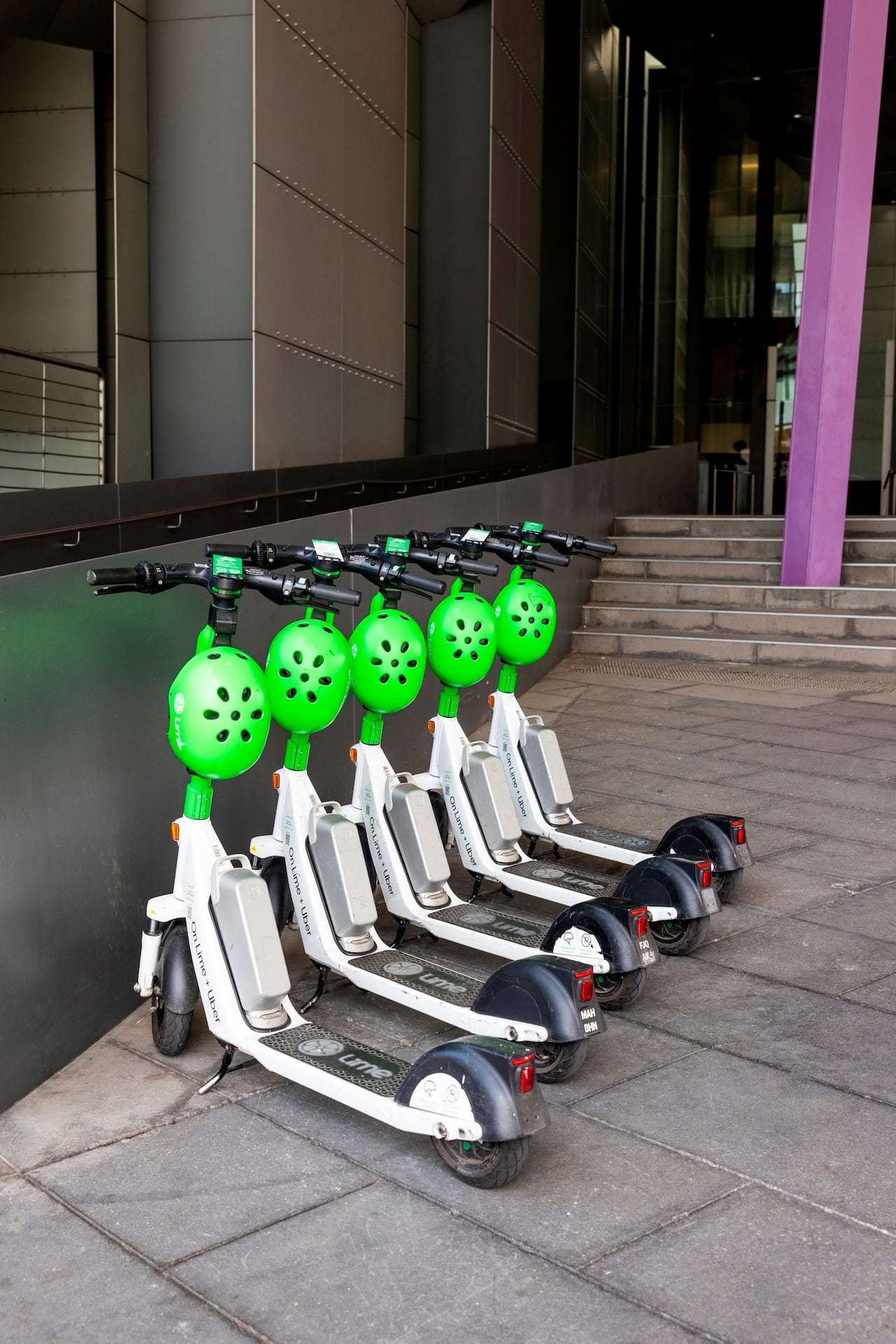 Five Lime e-scooters are pictured in front of a building.