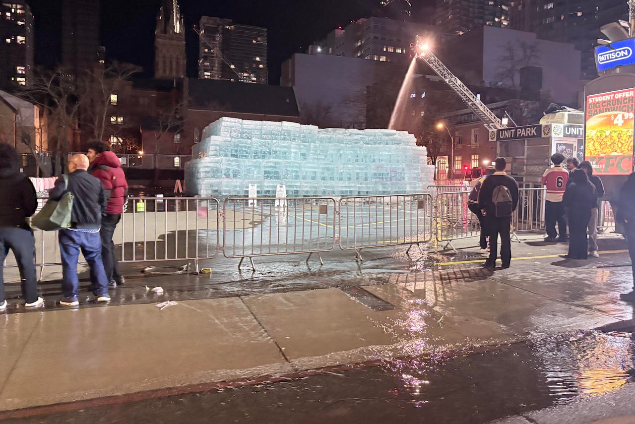 People gather as Toronto Fire crews melt some ice blocks that caused flooding on roads.