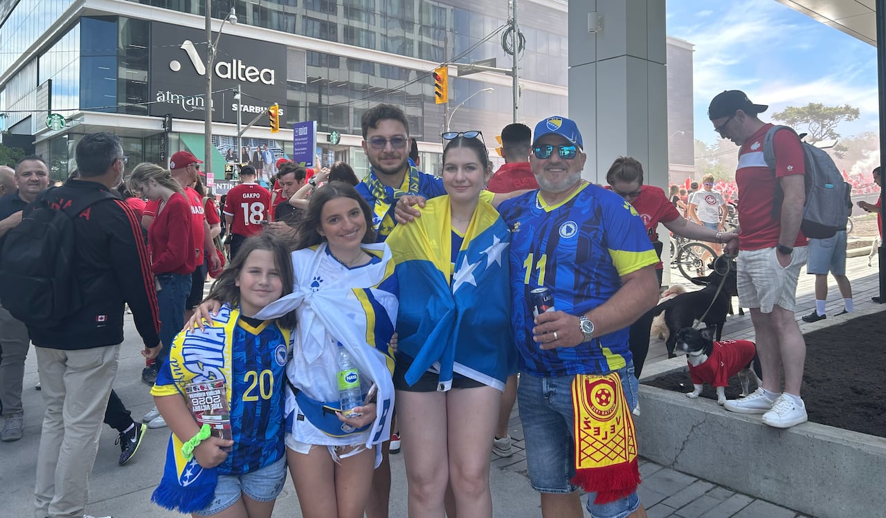 Fans wearing team Bosnia colours before a crowded street.