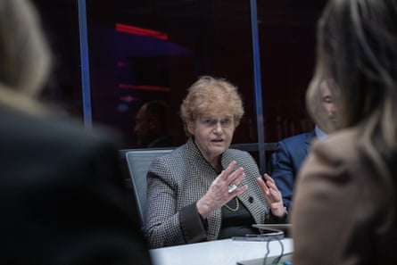 Woman in gray suit jacket speaking at table.