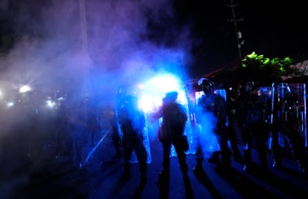 police stand guard as teargas blooms