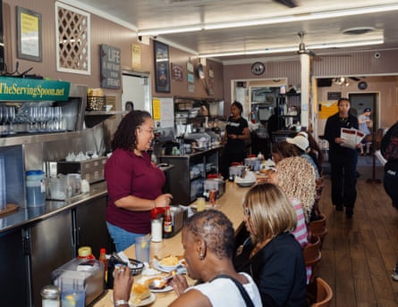 the owner of a diner in burgundy serves customers seated at the counter