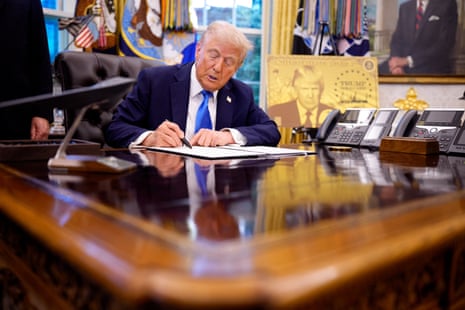 a man signs a document while seated at a desk