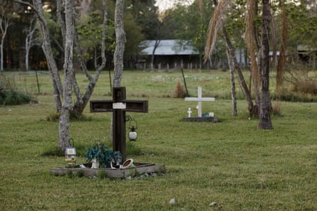 A grassy field surrounded by trees, with crosses marking graves and memorials.