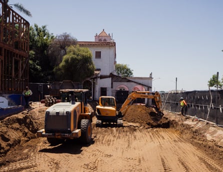 two bulldozers are seen on a construction project at a church which is seen in the background