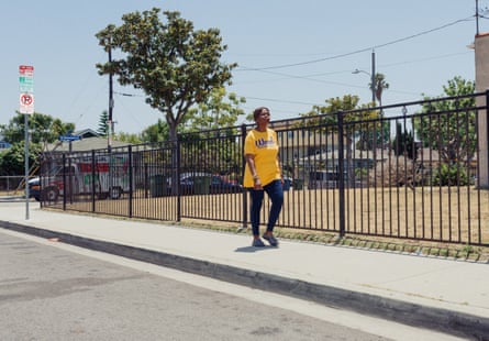 a woman in a yellow shirt walks down the street in a residential neighborhood