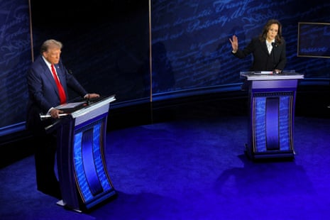 Kamala Harris gestures while speaking as Donald Trump listens at podium on a debate stage