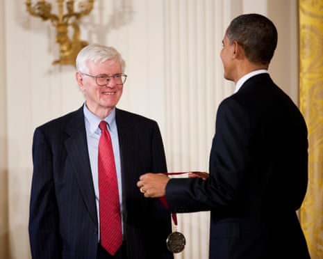 a man smiles at another man holding a medal