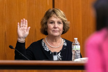 a woman raises her hand in the witness stand