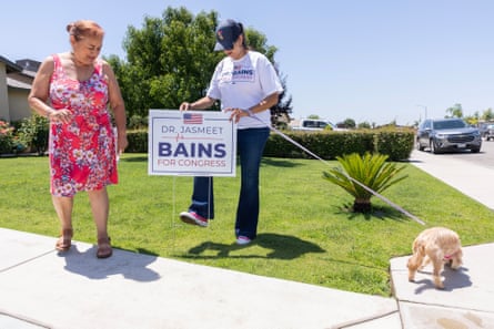 a woman places a campaign sign in a yard